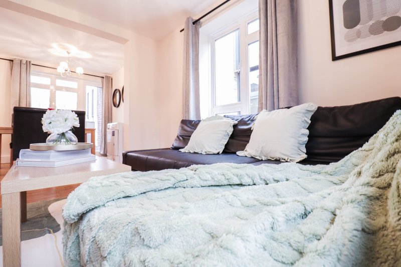 Bright bedroom with double bed, black sofa, window with curtains and open doorway