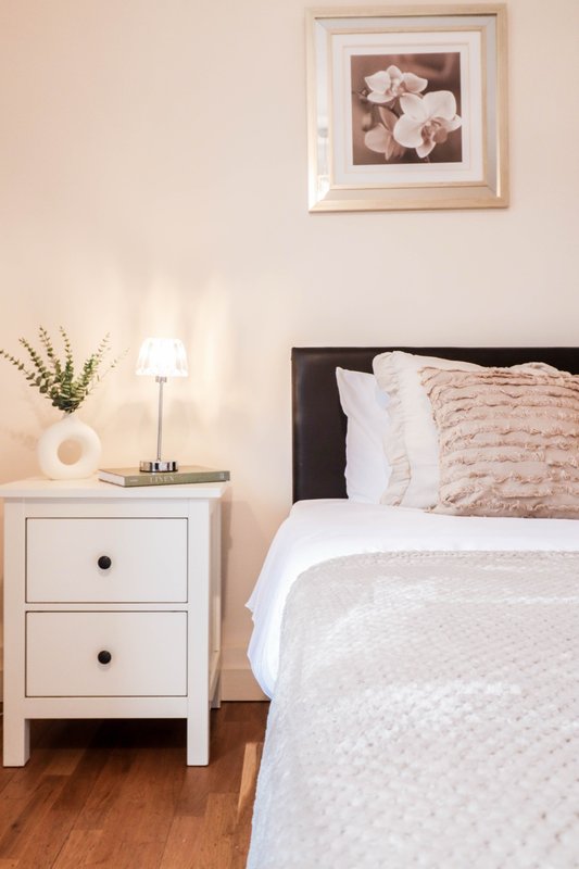 Bedroom with double bed, white bedding, black headboard, and wooden nightstand with lamp