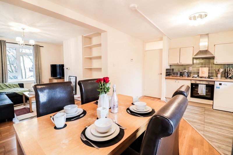 Open-plan kitchen and dining area with wooden table, black leather chairs, and modern appliances