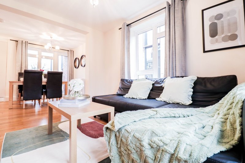 Open-plan living room with bed, sofa, dining table and kitchen visible through doorway