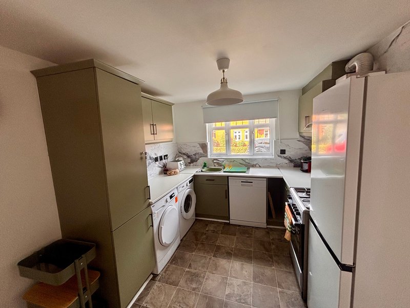 Modern kitchen with white appliances, fitted cabinetry, tiled floor and window