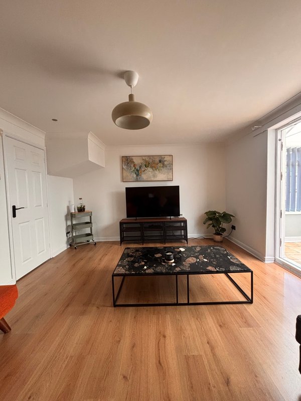 Spacious living room with wooden flooring, TV unit, coffee table and ceiling fan