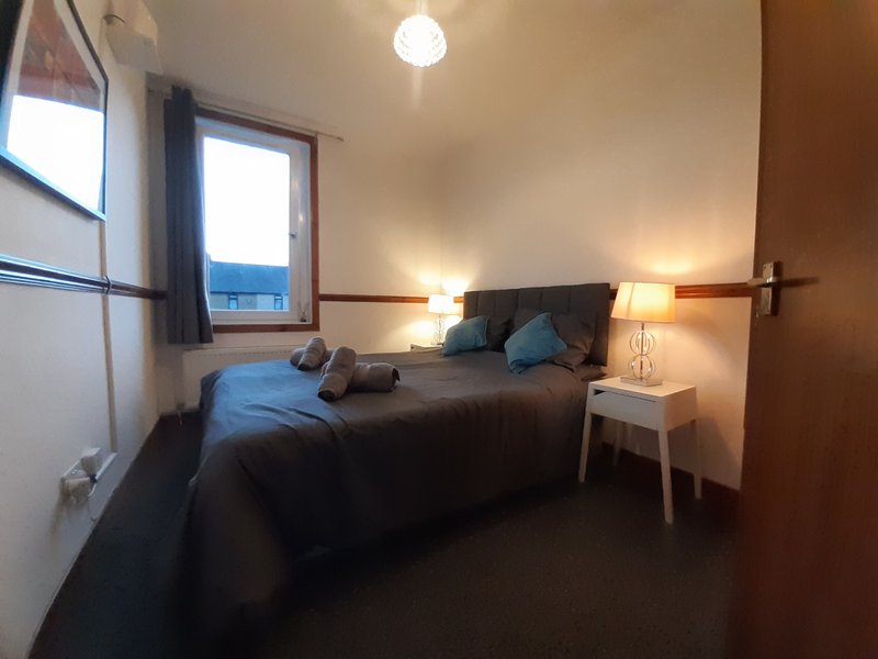Bedroom with double bed, bedside tables, lamps, and windows with views
