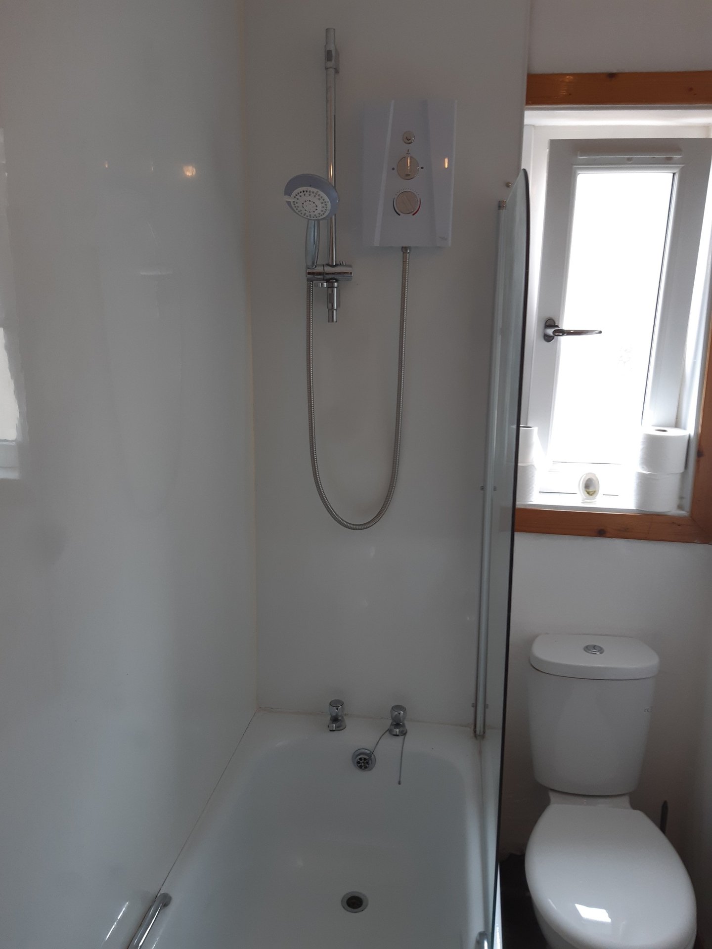 Compact bathroom with walk-in shower, toilet, and small window