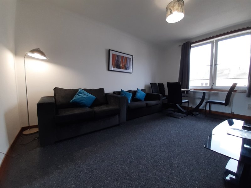 Modern living room with black sofa, blue cushions, floor lamp and large window