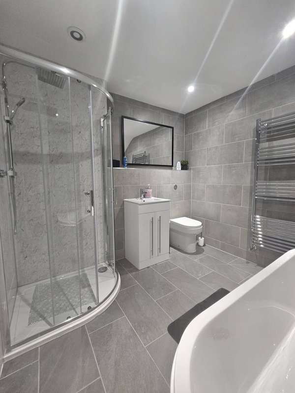 Modern bathroom with curved shower enclosure, vanity unit, mirror and heated towel rail