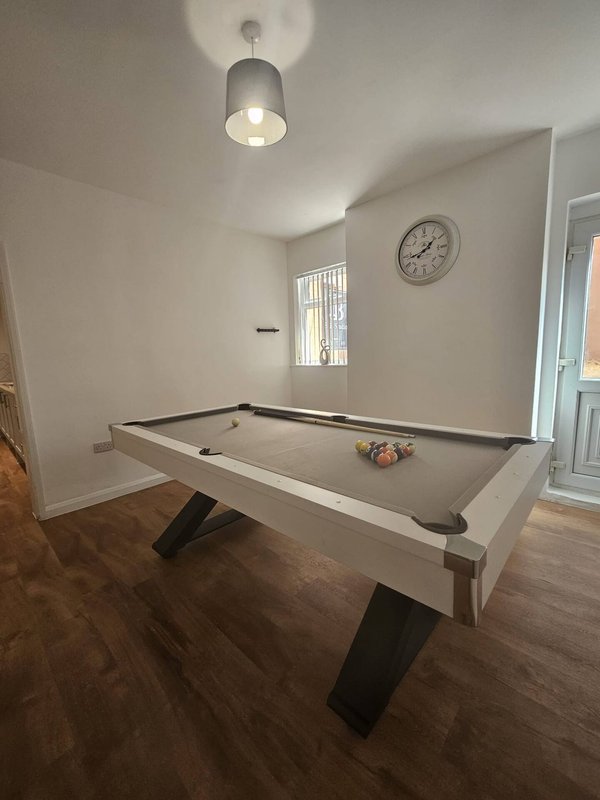Game room with pool table, ceiling light fixture, wall clock, and window.