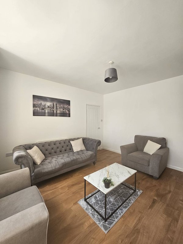 Living room with gray sofa, armchair, white coffee table and framed wall art