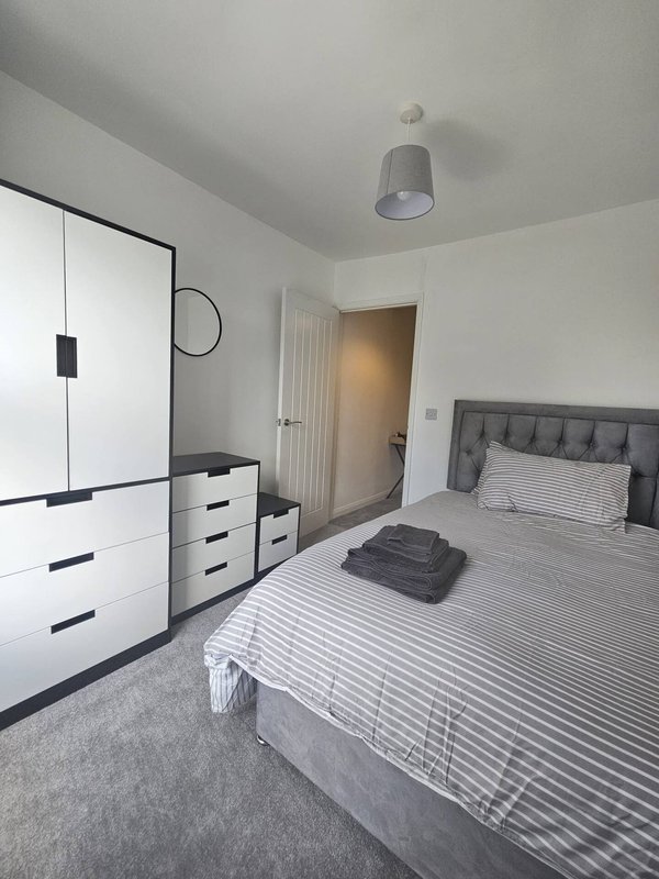 Modern bedroom with striped bed, white wardrobe, gray headboard and pendant light