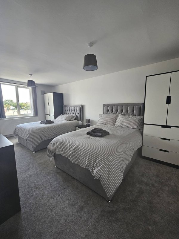 Modern bedroom with two double beds, grey carpet, pendant lights and built-in wardrobe