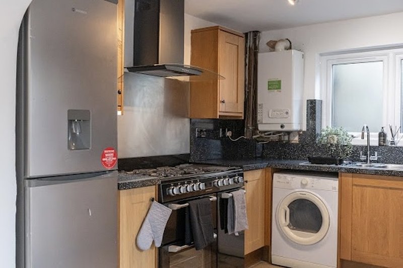 Modern kitchen with wooden cabinets, stainless steel appliances, black range cooker, and granite countertops