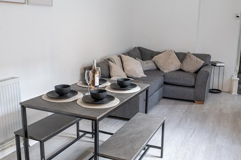 Modern living room with gray sofa, dining table set, and neutral cushions