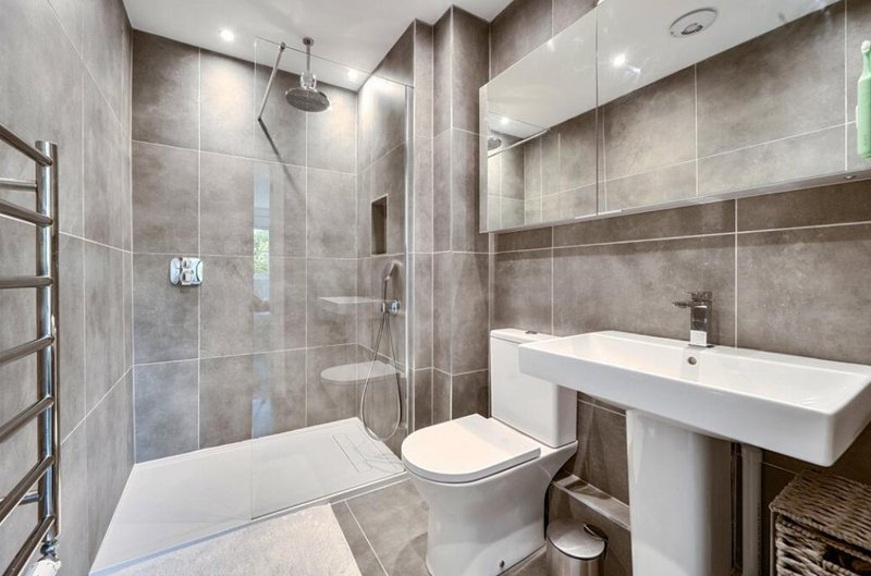 Modern bathroom with walk-in shower, toilet, white basin and heated towel rail