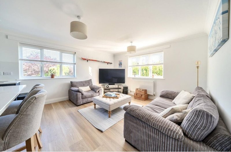 Bright living room with two sofas, TV, coffee table, windows and wooden flooring