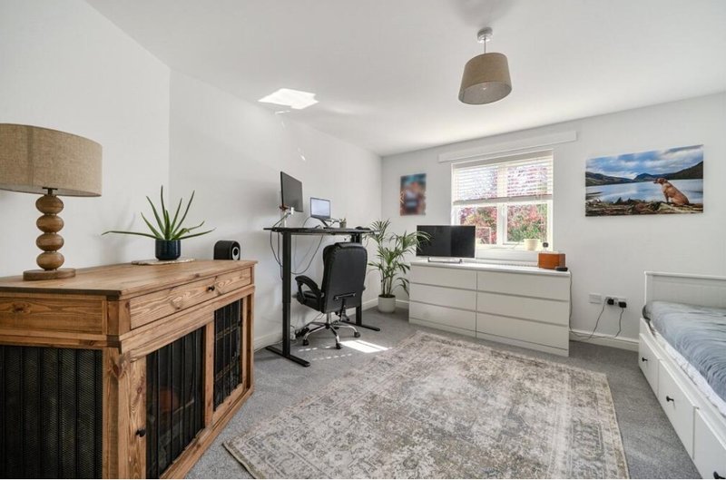 Bright bedroom with desk workspace, wooden furniture, bed, and large window with countryside view