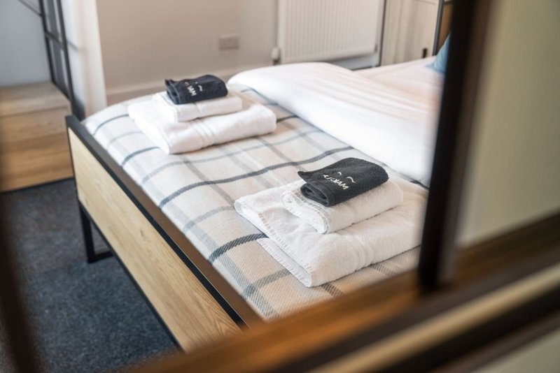 Bedroom with double bed, folded towels, and remote controls on mattress