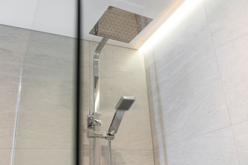 Modern bathroom shower with rainfall showerhead, handheld spray, and light tiled walls