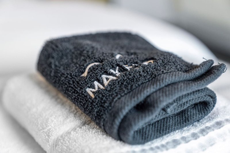 Folded dark grey towel with brand embroidery on white towel background