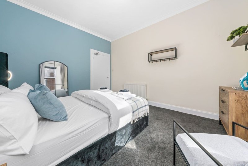 Bedroom with double bed, blue accent wall, wooden furniture and second bed