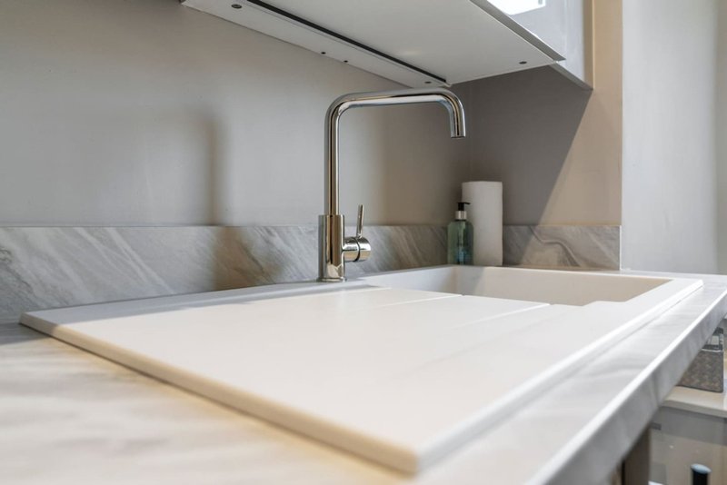 Modern kitchen sink with marble backsplash, chrome faucet and white countertop