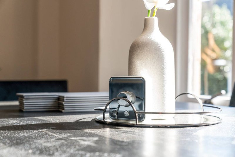 Modern kitchen counter with vase, flowers, phone stand, earbuds and magazines