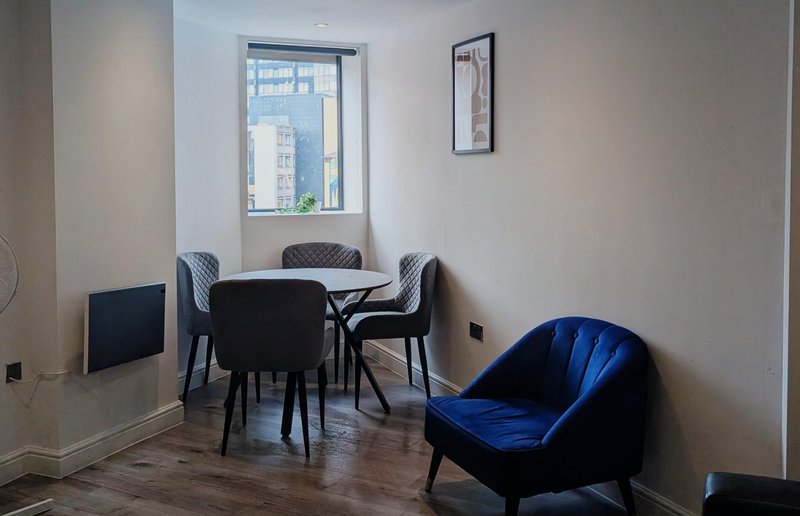 Modern dining area with black table, chairs, blue accent chair and window view