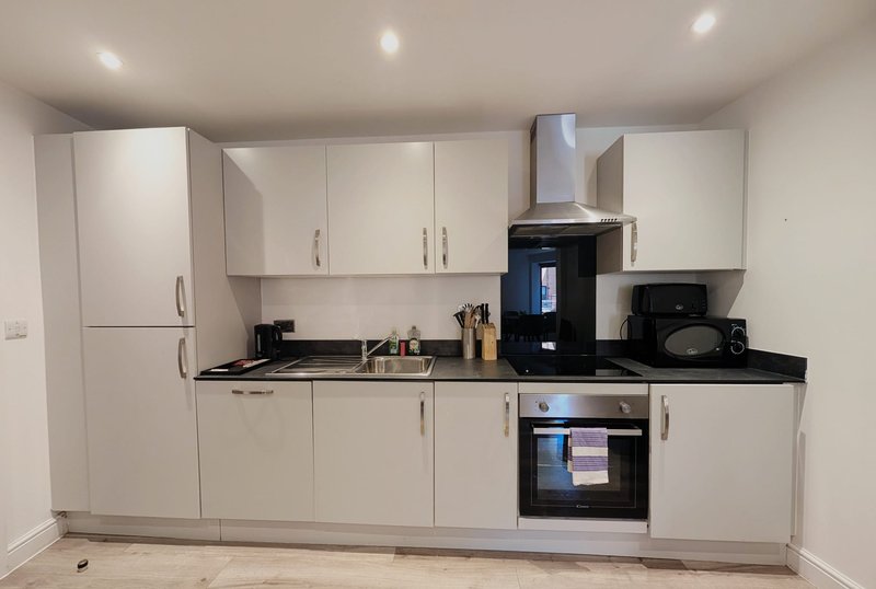 Modern kitchen with white cabinetry, black countertop, built-in oven and black appliances