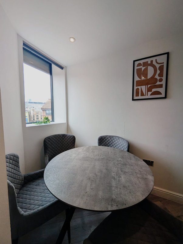 Modern dining nook with round table, two quilted chairs and city view window