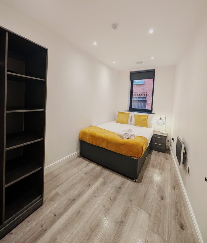 Modern bedroom with single bed, yellow bedding, black wardrobe and window with blinds
