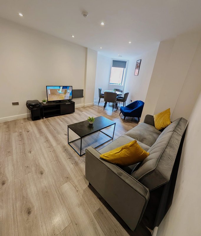 Modern open-plan living room with grey sofa, TV, dining area and blue armchair
