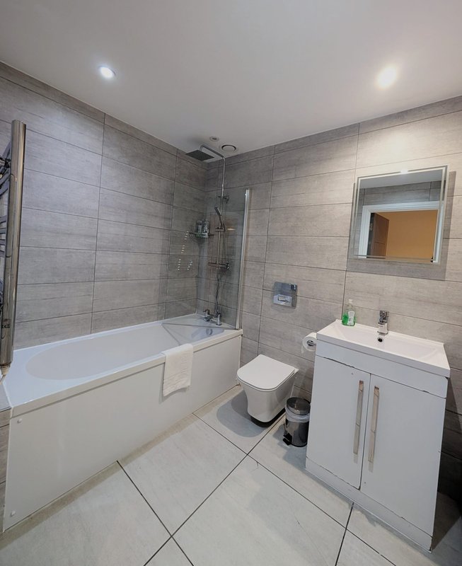 Modern bathroom with bathtub, shower enclosure, white vanity sink and toilet