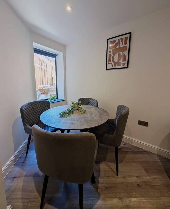 Dining room with round table, four upholstered chairs, window with view, and framed wall art