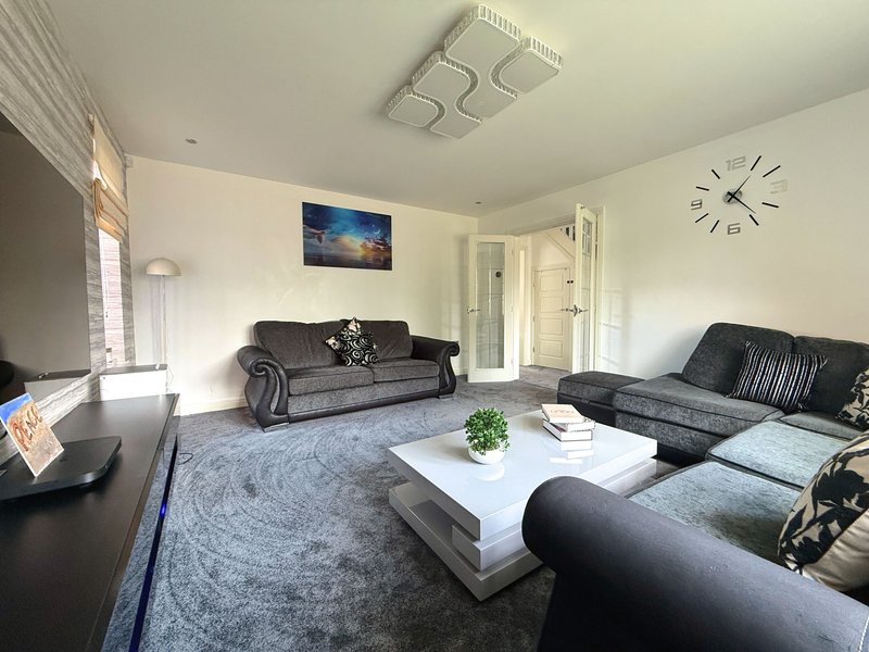 Modern living room with grey sofas, white coffee table, wall clock and framed artwork