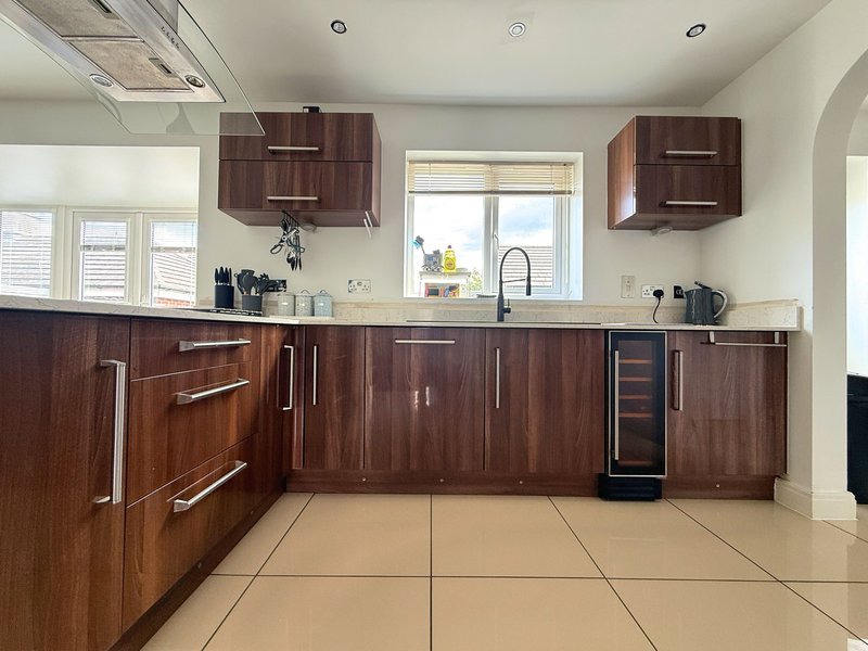 Modern kitchen with dark wood cabinets, beige tile flooring, stainless steel appliances and windows