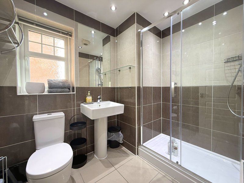 Modern bathroom with toilet, pedestal sink, shower enclosure and window