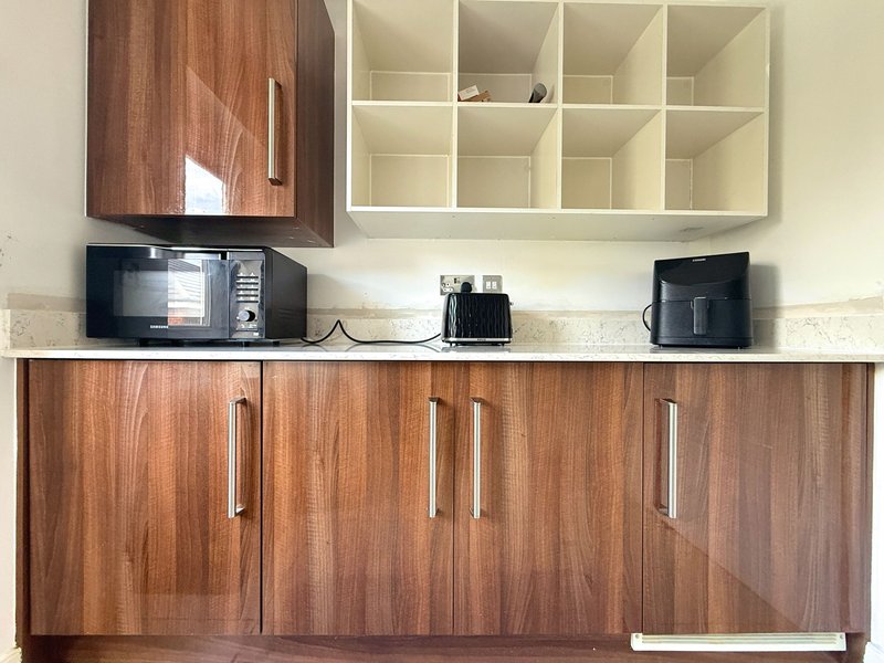 Kitchen with wooden cabinets, cream countertop, wall-mounted shelving and small appliances