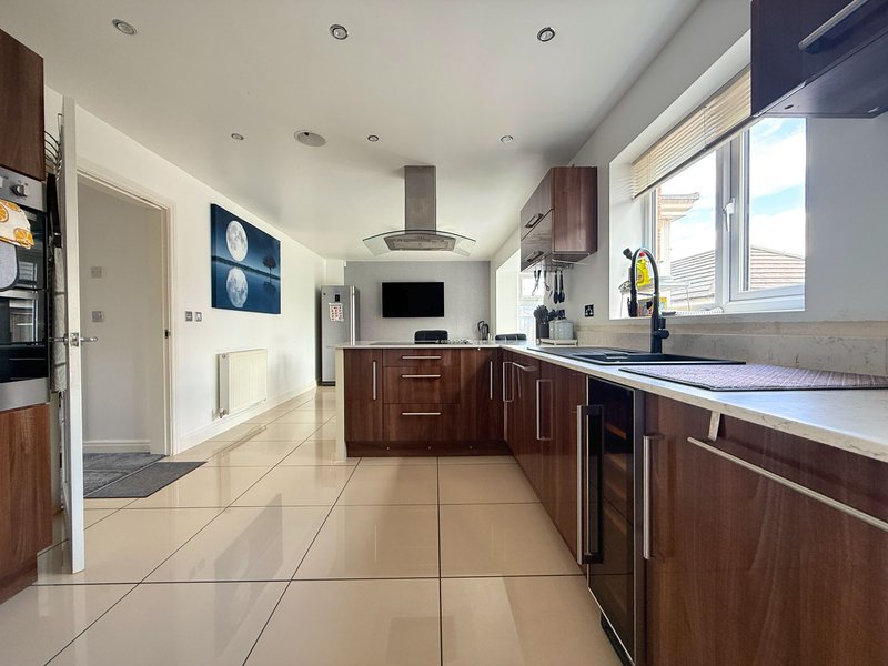 Modern kitchen with dark wood cabinets, stainless steel appliances, and large windows