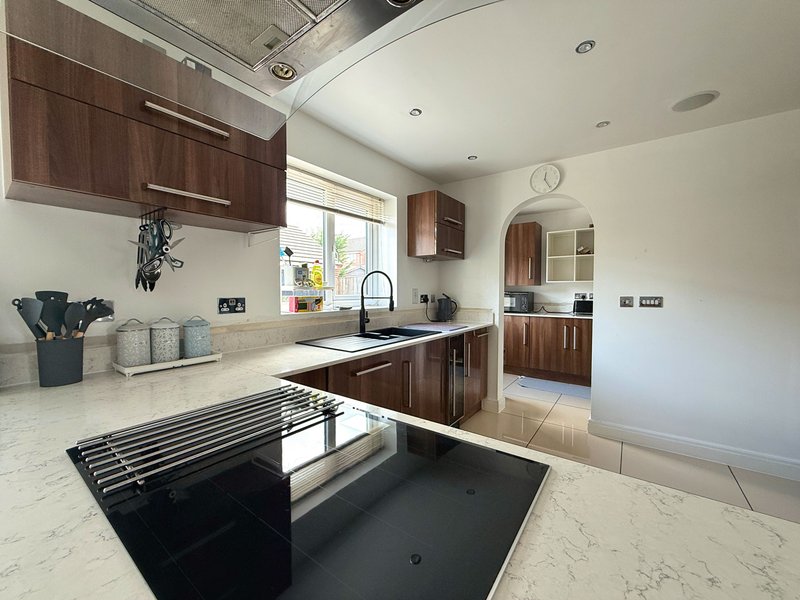 Modern kitchen with dark wood cabinets, marble countertops, central island and stainless steel appliances