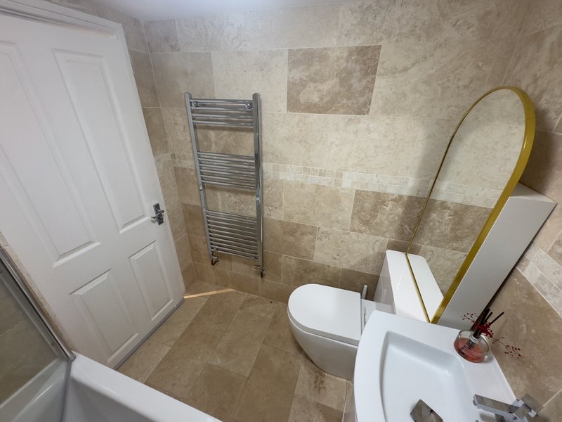 Bathroom with toilet, sink, heated towel rail, mirror and tiled walls