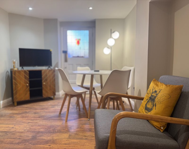 Modern living room with sofa, armchair, dining table, TV stand and floor lamp