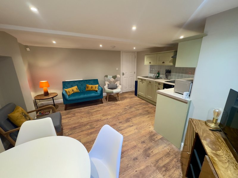 Open-plan living space with kitchen, dining table, blue sofa and orange lamp