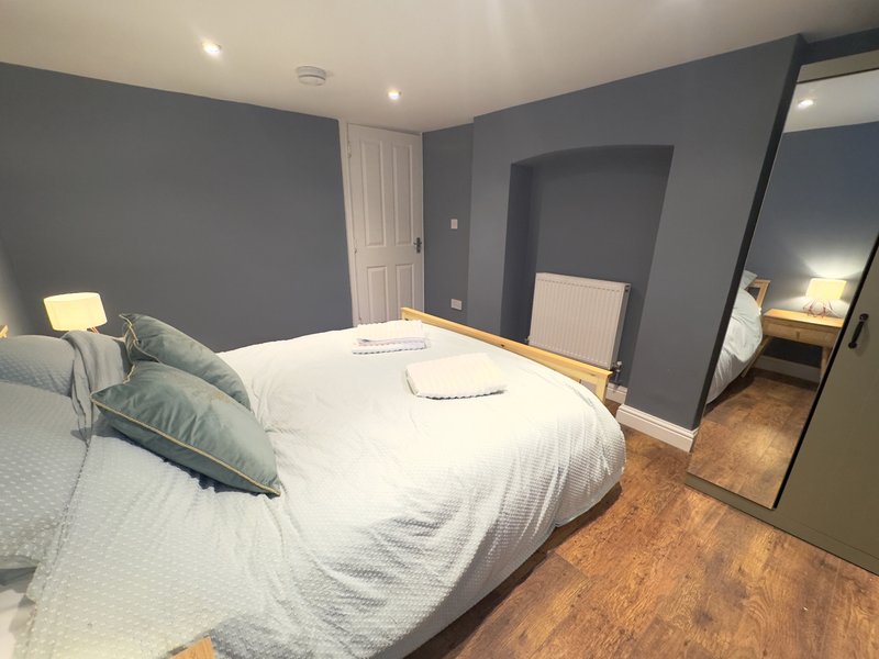Modern bedroom with double bed, grey walls, wooden floor and ensuite bathroom
