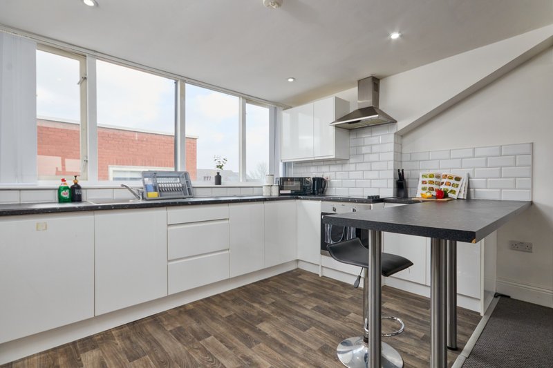 Modern kitchen with white cabinetry, black countertops, island, and large windows overlooking brick building