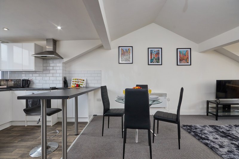 Open-plan kitchen and dining area with black dining table, modern kitchen island, and wall art