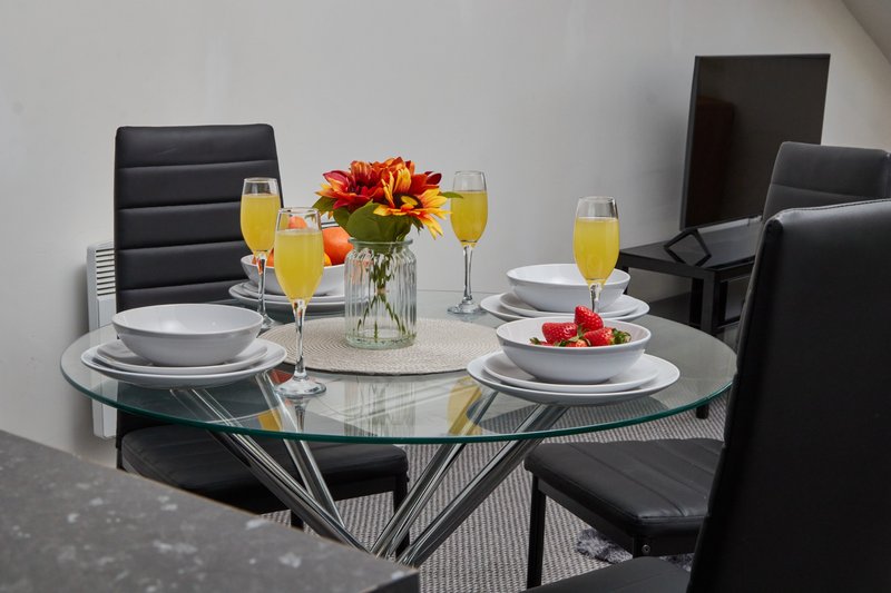 Modern dining table set with place settings, flowers, and orange juice glasses