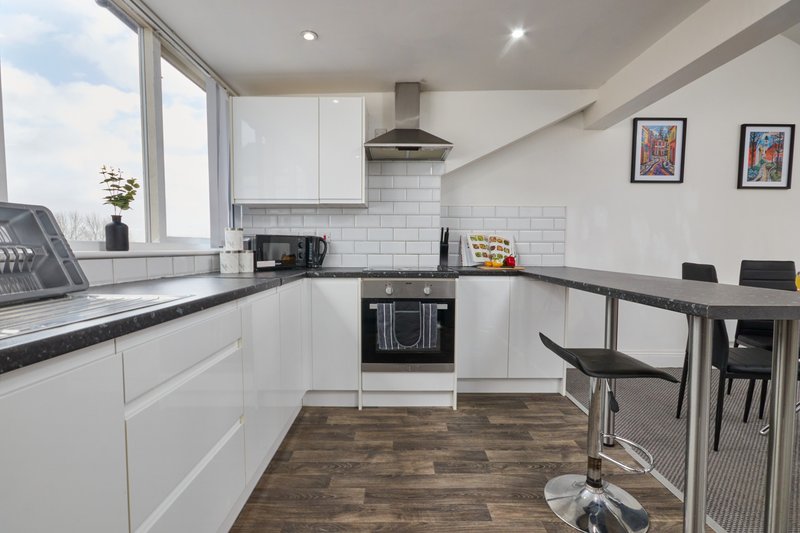 Modern kitchen with white cabinetry, black countertops, subway tile backsplash, and dining area