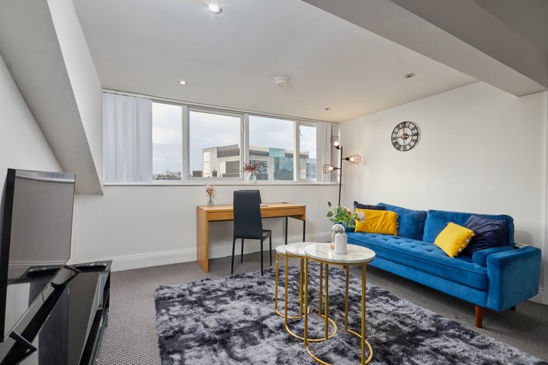 Modern living room with blue sofa, wooden desk, round coffee table and city views