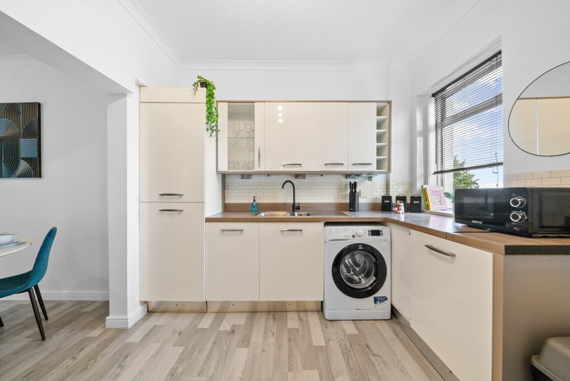 Modern kitchen with cream cabinetry, wooden countertops, washing machine and integrated appliances