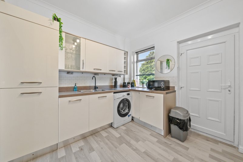 Modern kitchen with cream cabinets, washing machine, wooden countertop and vinyl flooring
