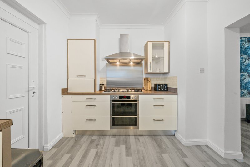 Modern kitchen with cream cabinetry, built-in oven, wooden countertop, and stainless steel appliances